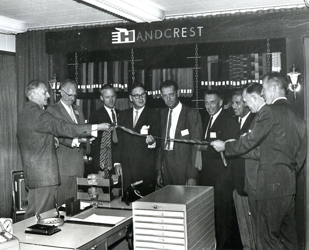 Lighthouse and Handcrest executives cutting a ceremonial necktie to celebrate the merger of the two companies